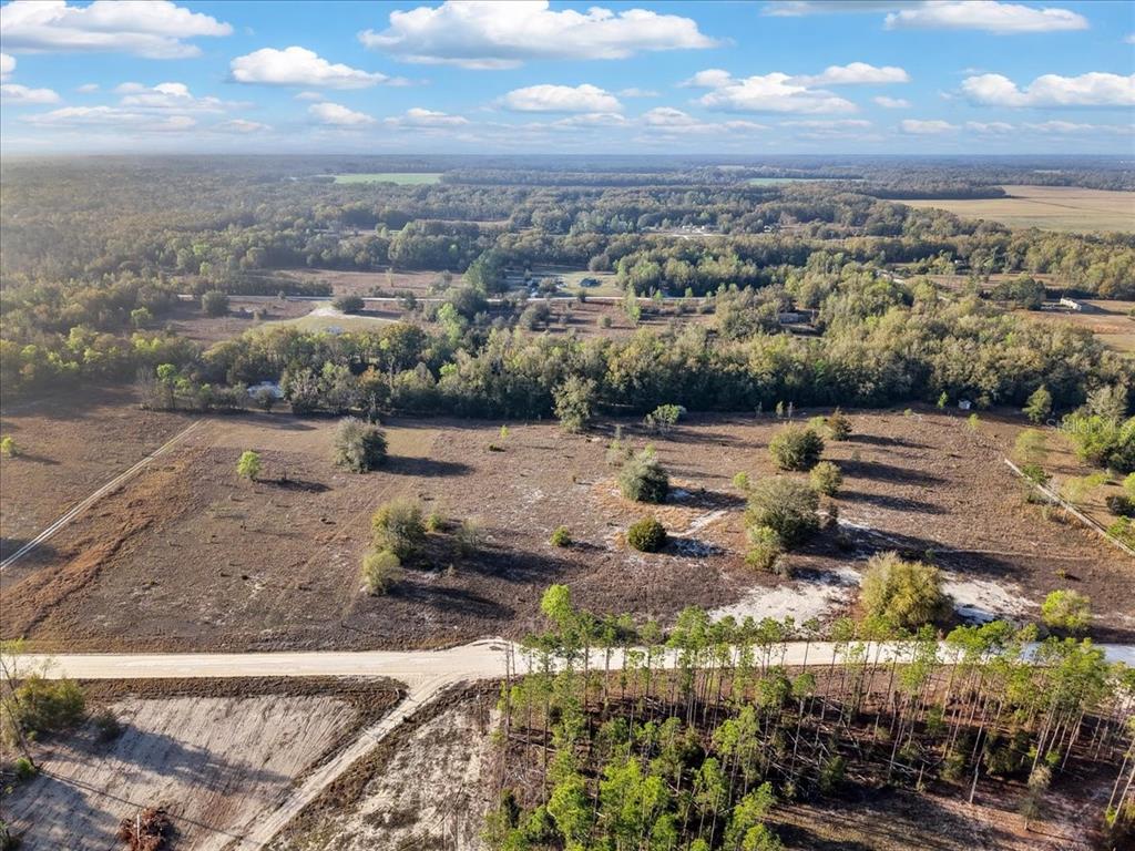 An aerial view shows a large, cleared plot of land bordered by trees and roads — TBD 000 NW 98TH LANE, BRANFORD, FL