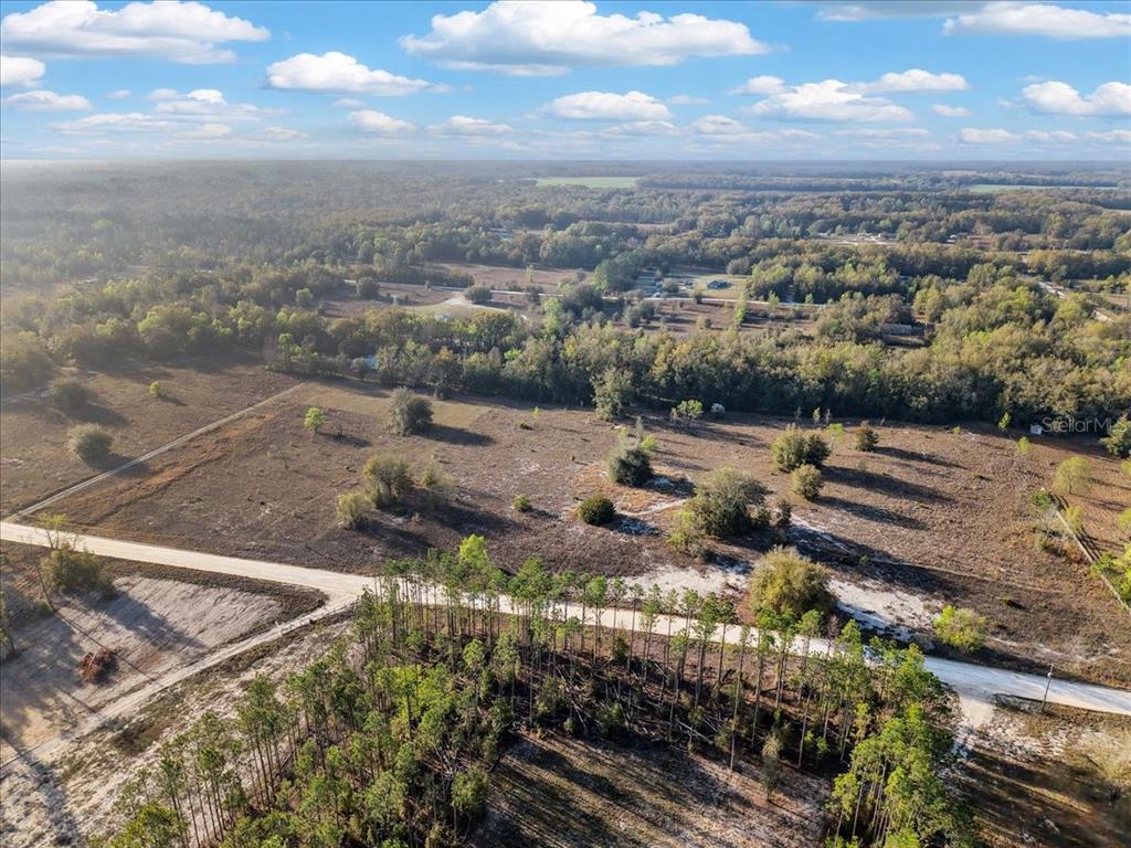 An aerial view shows a large, cleared plot of land bordered by trees and roads — TBD 000 NW 98TH LANE, BRANFORD, FL