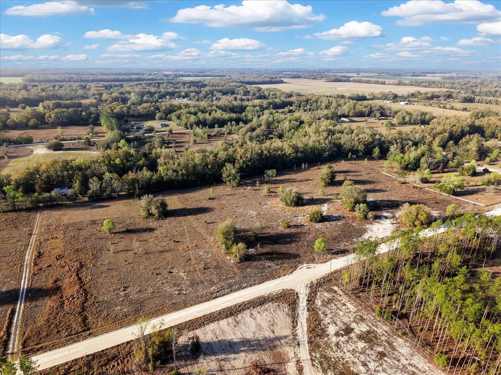 An aerial view shows a large, undeveloped rural lot with dirt roads and scattered trees — TBD 000 NW 98TH LANE, BRANFORD, FL