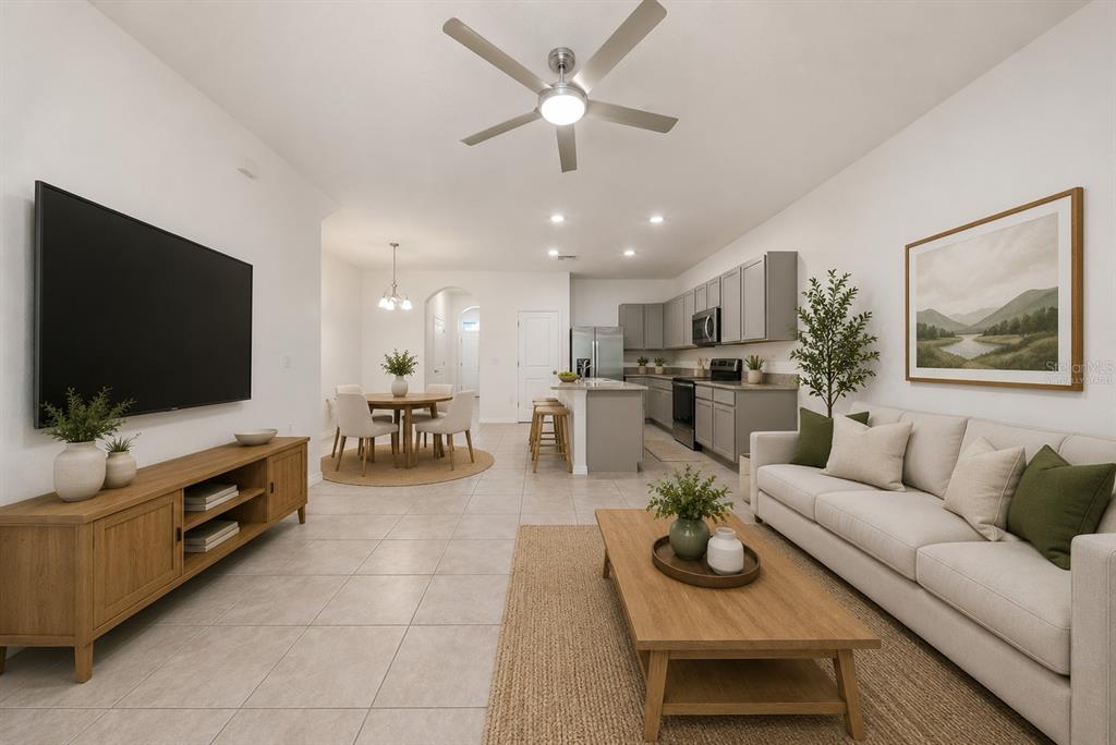 An open-concept living room and kitchen with tile flooring, gray cabinetry, and neutral furniture — 1574 HUBBELL ROAD, WESLEY CHAPEL, FL