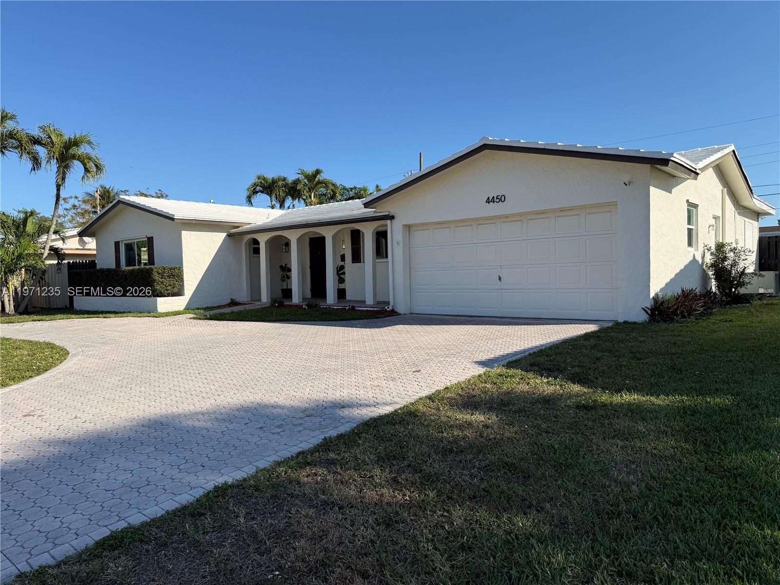 A single-story white house features a paved driveway, a garage, and an arched entryway — 4450 NW 9th St, Coconut Creek FL 33066, COCONUT CREEK, FL
