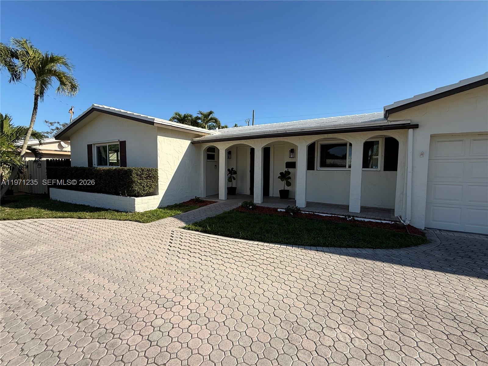 A single-story house with a white stucco exterior, arched porch, and a paved driveway — 4450 NW 9th St, Coconut Creek FL 33066, COCONUT CREEK, FL