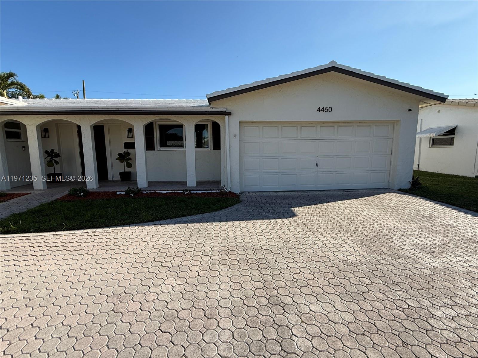 A single-story house features a white stucco exterior, a paved driveway, and an arched entryway — 4450 NW 9th St, Coconut Creek FL 33066, COCONUT CREEK, FL