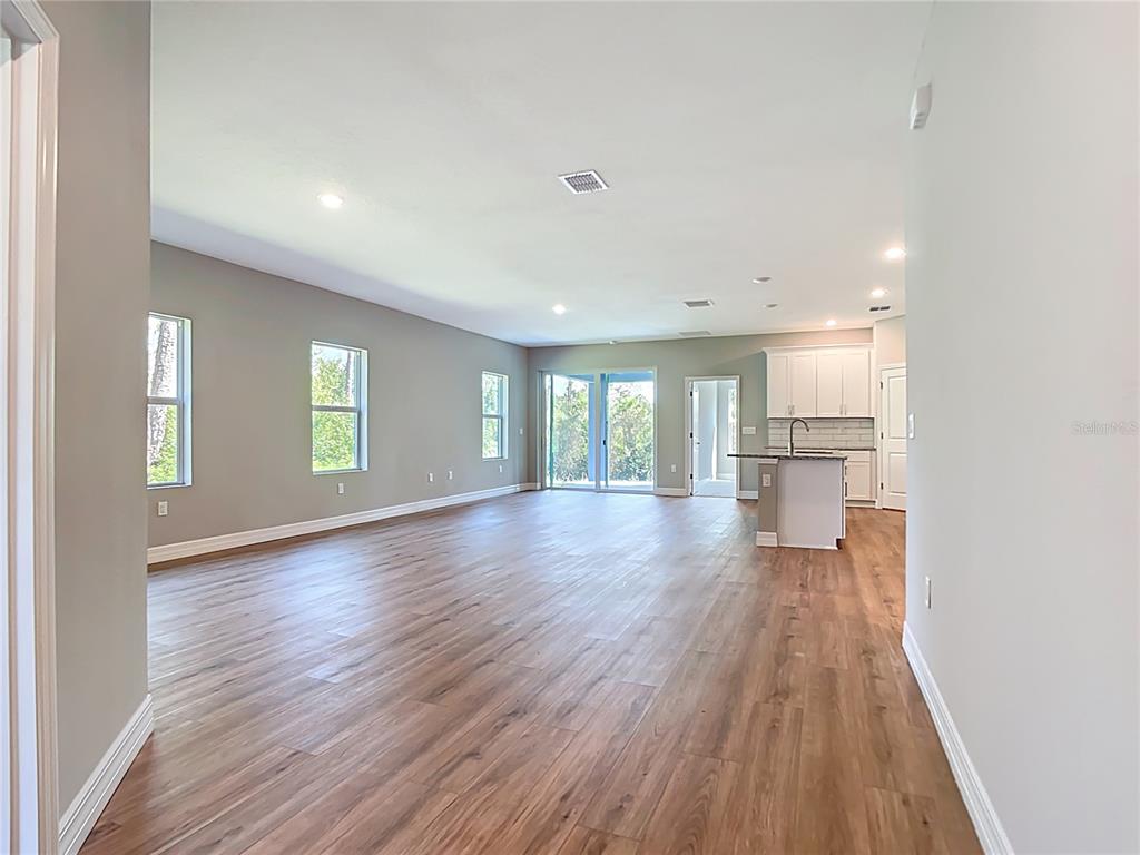 An open-concept living area features wood-look flooring, light gray walls, and a kitchen with white cabinetry — 2144 SADNET LANE, NORTH PORT, FL