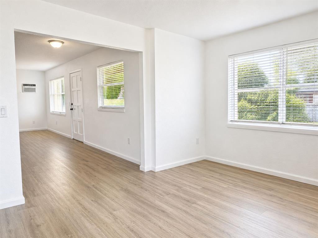 An empty room with light wood-look flooring, white walls, and windows with white blinds — 2007 9TH STREET NE, WINTER HAVEN, FL
