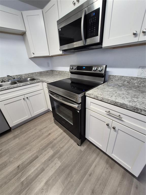 A kitchen features white cabinets, stainless steel appliances, and gray speckled laminate countertops — 2007 9TH STREET NE, WINTER HAVEN, FL