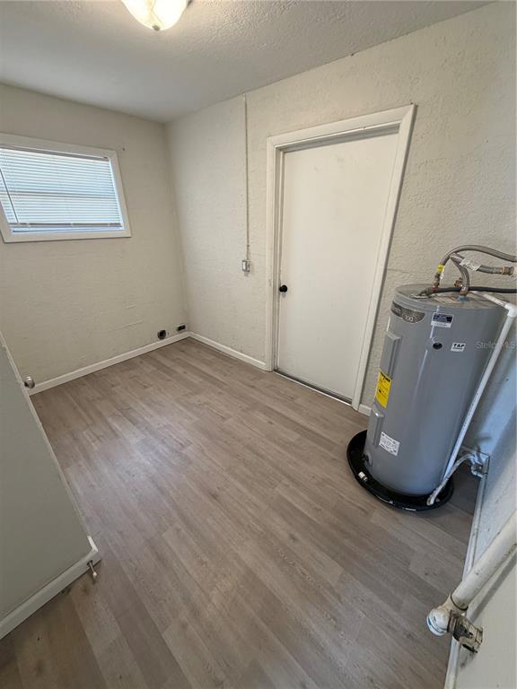 A utility room with light wood-look flooring, a white door, and a water heater — 2007 9TH STREET NE, WINTER HAVEN, FL