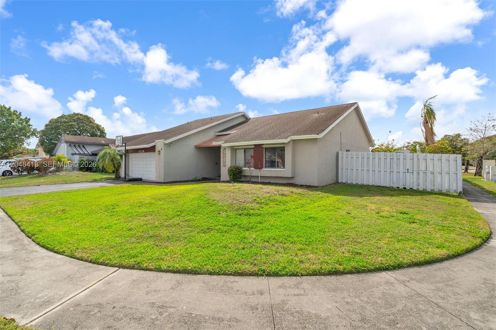 A single-story house with a beige exterior, a two-car garage, and a white privacy fence — 8650 NW 46th Ct, Lauderhill FL 33351, LAUDERHILL, FL