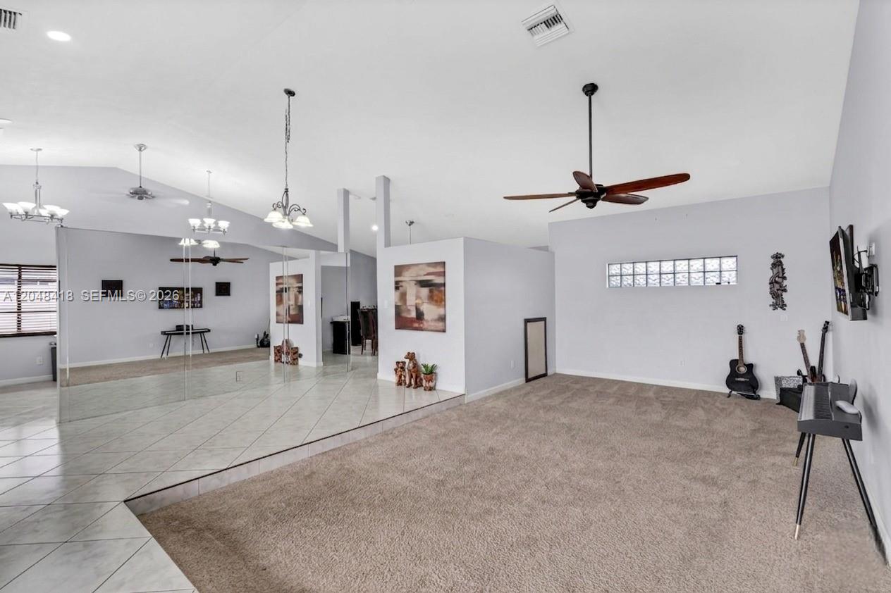 A living room features a carpeted area, a tiled section with mirrored walls, and vaulted ceilings — 8650 NW 46th Ct, Lauderhill FL 33351, LAUDERHILL, FL