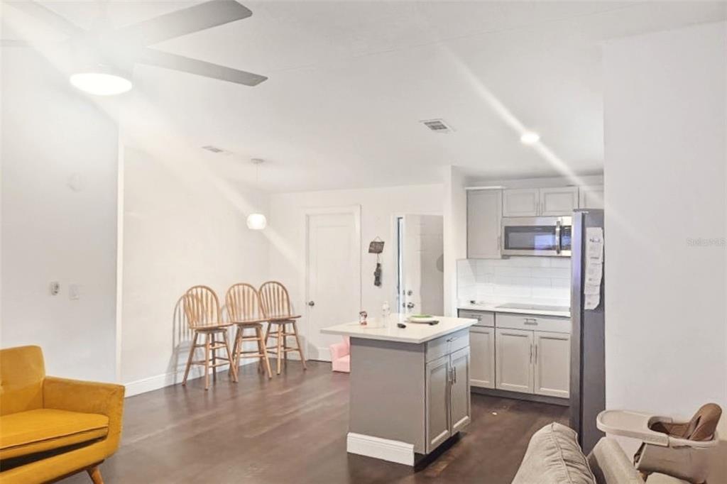 An open-concept kitchen and living area features a central island, bar stools, and hardwood floors — 5521 SHARON AVENUE, INTERCESSION CITY, FL