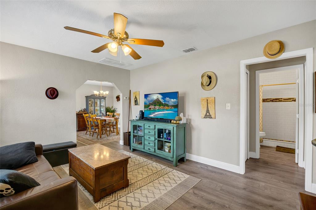 A living room with a ceiling fan, television on a teal console, and dining area — 104 AVENUE K AVENUE NE, WINTER HAVEN, FL