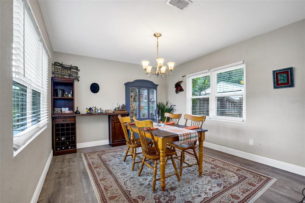 A dining room features a wooden table, chairs, a hutch, and a wine rack — 104 AVENUE K AVENUE NE, WINTER HAVEN, FL
