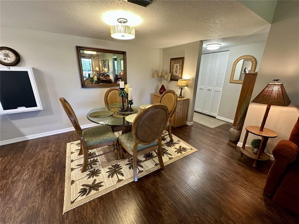 A dining room features a glass-topped table, four chairs, and a palm-patterned rug — 6116 43RD STREET W UNIT 401D, BRADENTON, FL