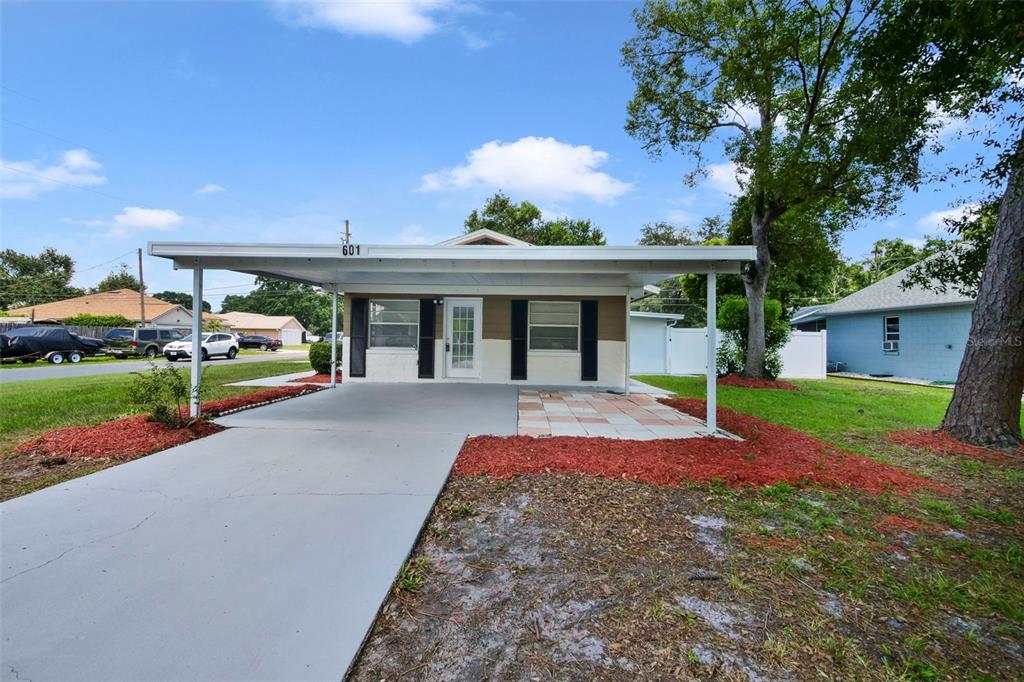 A single-story house with a white carport and a concrete driveway under a blue sky — 601 LOUISIANA AVENUE, ST CLOUD, FL