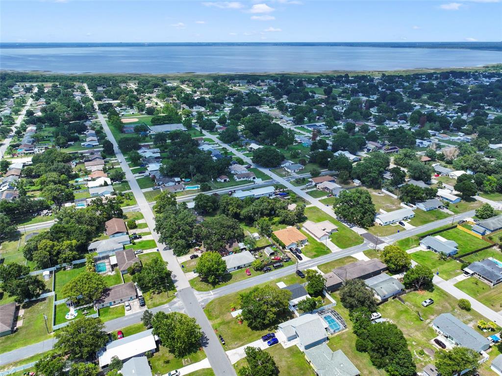 An aerial view shows a residential neighborhood with houses, trees, and a large lake nearby — 601 LOUISIANA AVENUE, ST CLOUD, FL