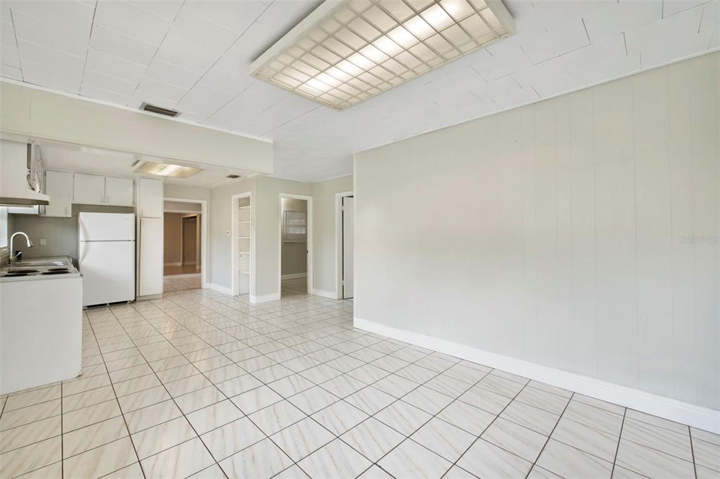 A kitchen and dining area with white tile floors, light walls, and a drop ceiling — 601 LOUISIANA AVENUE, ST CLOUD, FL