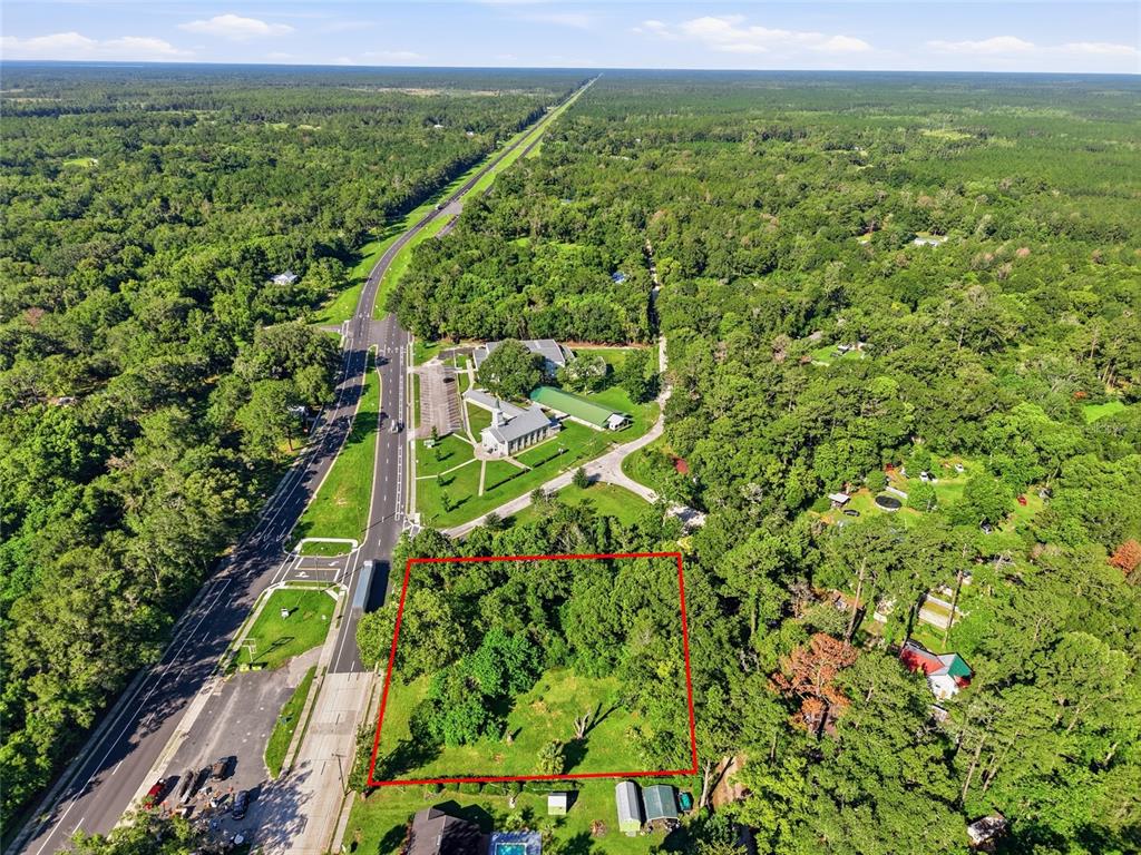 An aerial view shows a rectangular wooded lot outlined in red next to a highway — 00 SW 4TH BOULEVARD, WALDO, FL