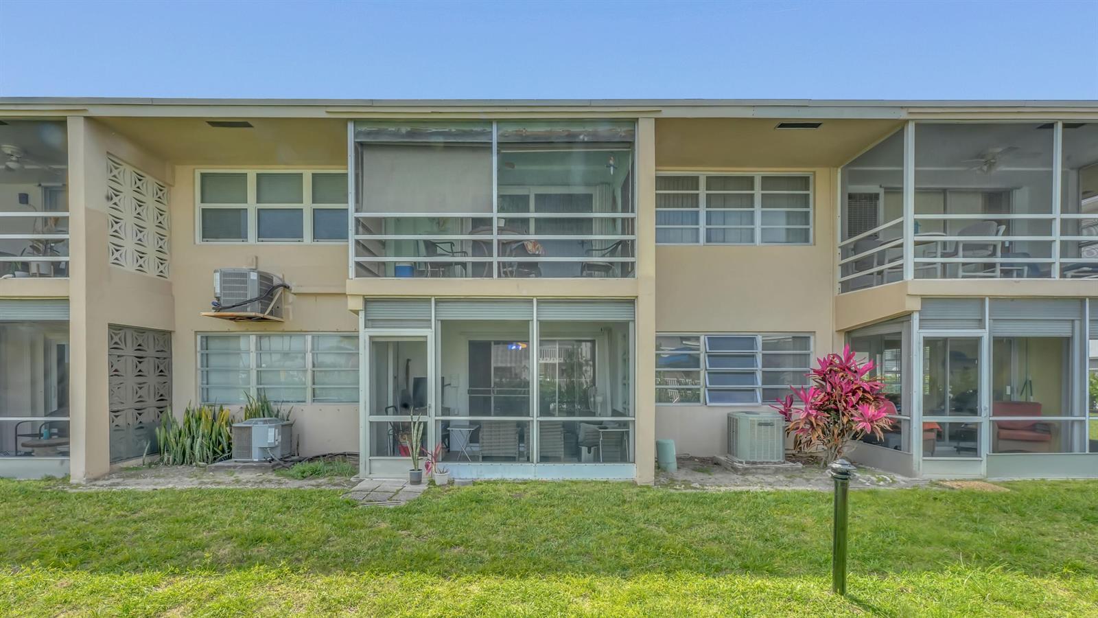 The exterior of a two-story apartment building features screened-in balconies and patios on both levels — 298 SE 6th Avenue # 2, Pompano Beach FL 33060, POMPANO BEACH, FL