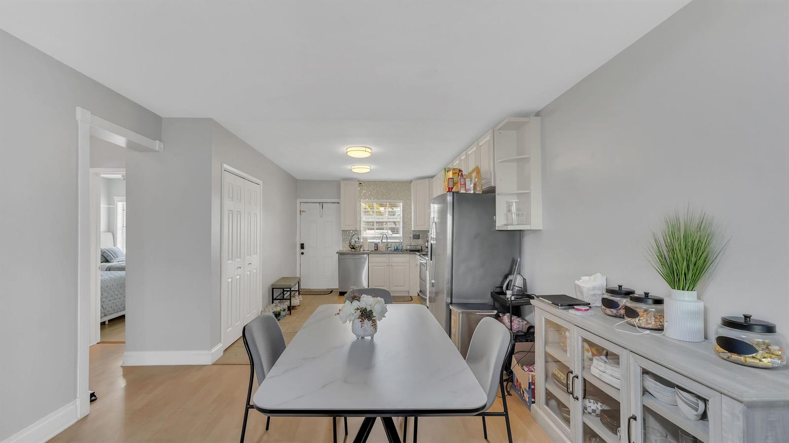 A dining area with a marble-top table leads into a kitchen with white cabinets — 298 SE 6th Avenue # 2, Pompano Beach FL 33060, POMPANO BEACH, FL