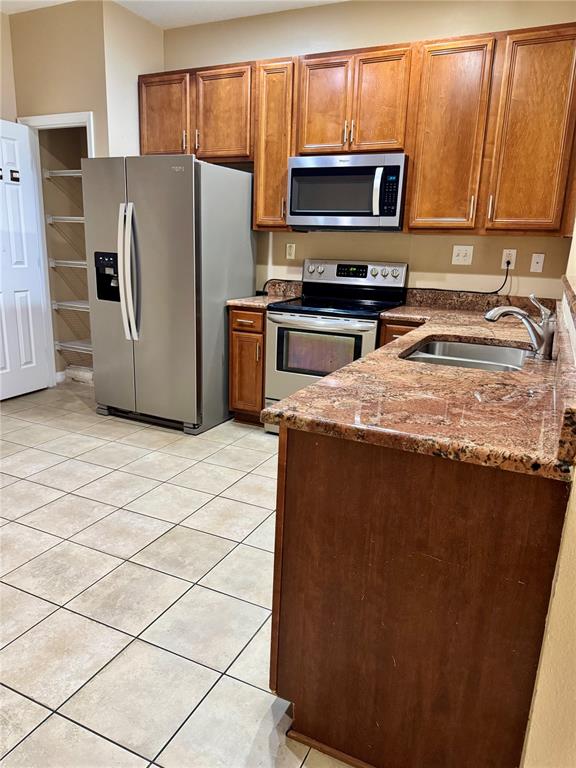 A kitchen features wood cabinets, stainless steel appliances, and granite countertops over tile flooring — 2680 MAYAGUANA STREET, KISSIMMEE, FL