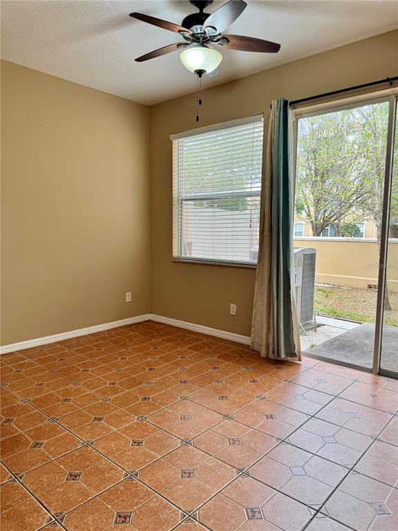 A room with tan walls, tiled flooring, a ceiling fan, a window, and sliding glass doors — 2680 MAYAGUANA STREET, KISSIMMEE, FL