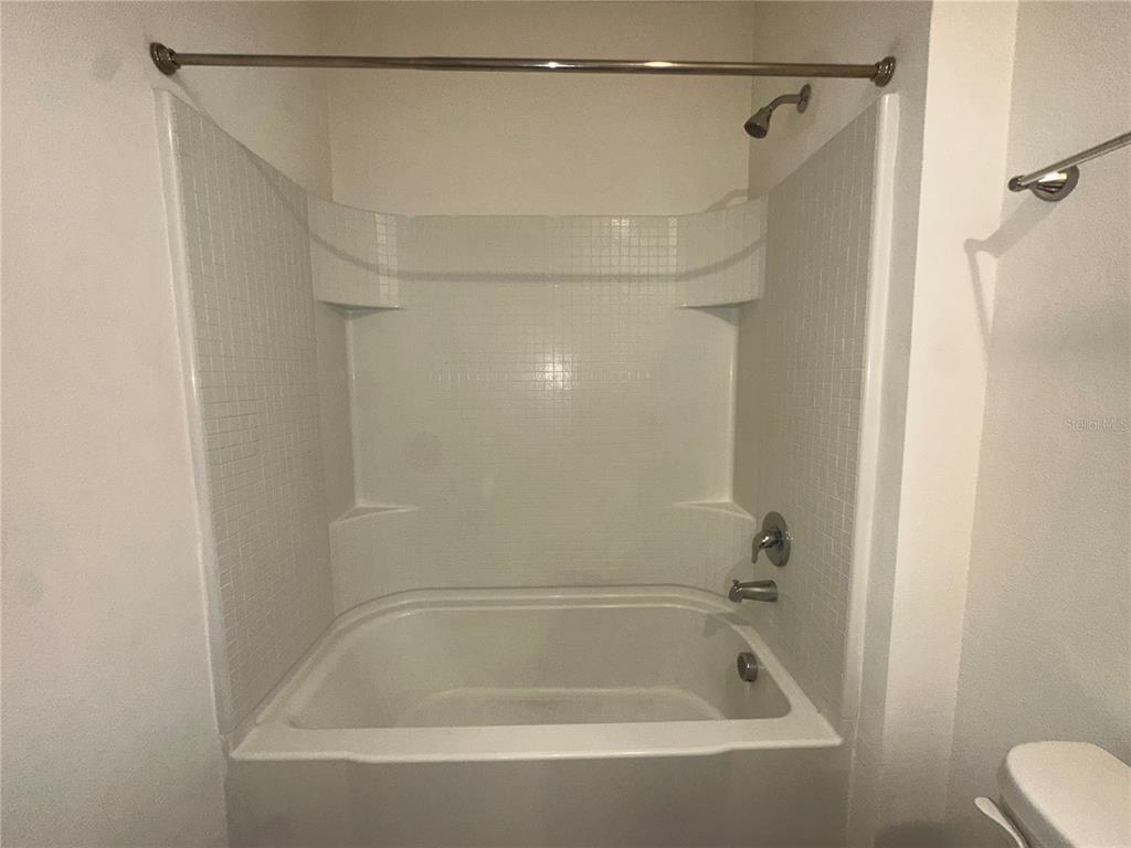 A white bathtub and shower combination with tiled walls and a metal shower rod — 1554 OAK RESERVE DRIVE, KISSIMMEE, FL