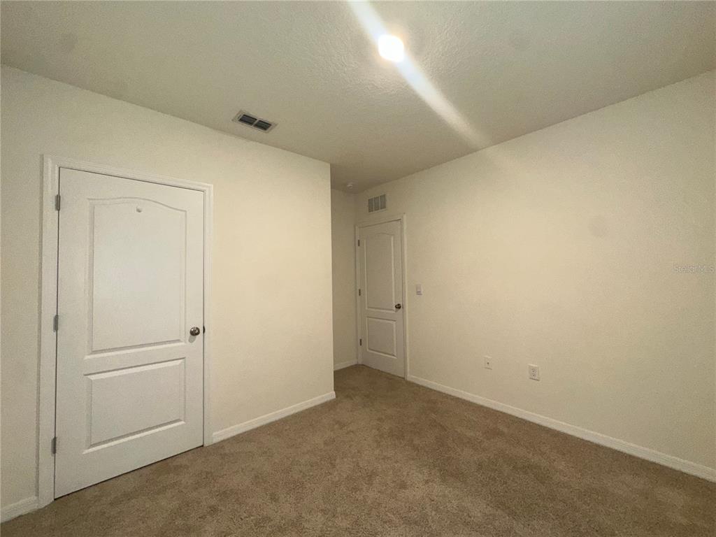 An empty room with beige carpet, white walls, and two closed interior doors — 1554 OAK RESERVE DRIVE, KISSIMMEE, FL
