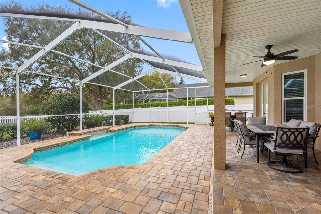 A screened-in patio features a swimming pool, paver flooring, and an outdoor dining set — 6224 ROCKROSS AVENUE, NEW PORT RICHEY, FL