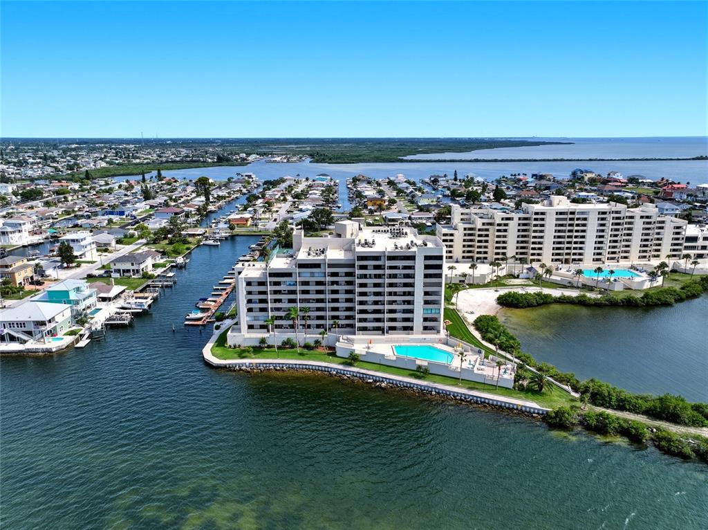 An aerial view shows two large waterfront condominium buildings with swimming pools on a peninsula — 6035 SEA RANCH DRIVE UNIT 902, HUDSON, FL