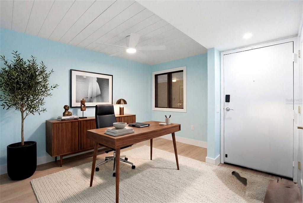 A home office with light blue walls, a wooden desk, and a white front door — 6035 SEA RANCH DRIVE UNIT 902, HUDSON, FL