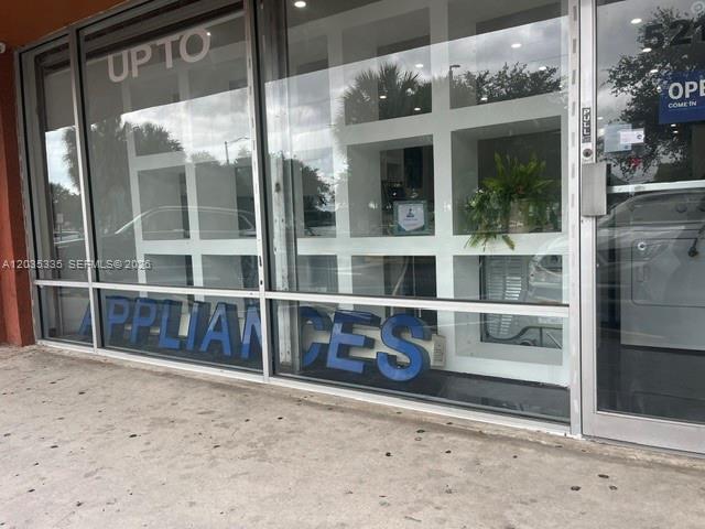 The exterior of a commercial storefront features large glass windows and blue lettering — TAMARAC, FL