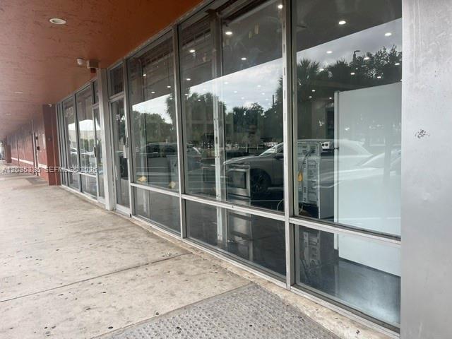 A view of a commercial storefront with large glass windows and a concrete sidewalk — TAMARAC, FL