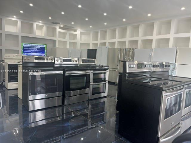 A showroom displays various stainless steel kitchen appliances against a wall of white cubbies — TAMARAC, FL