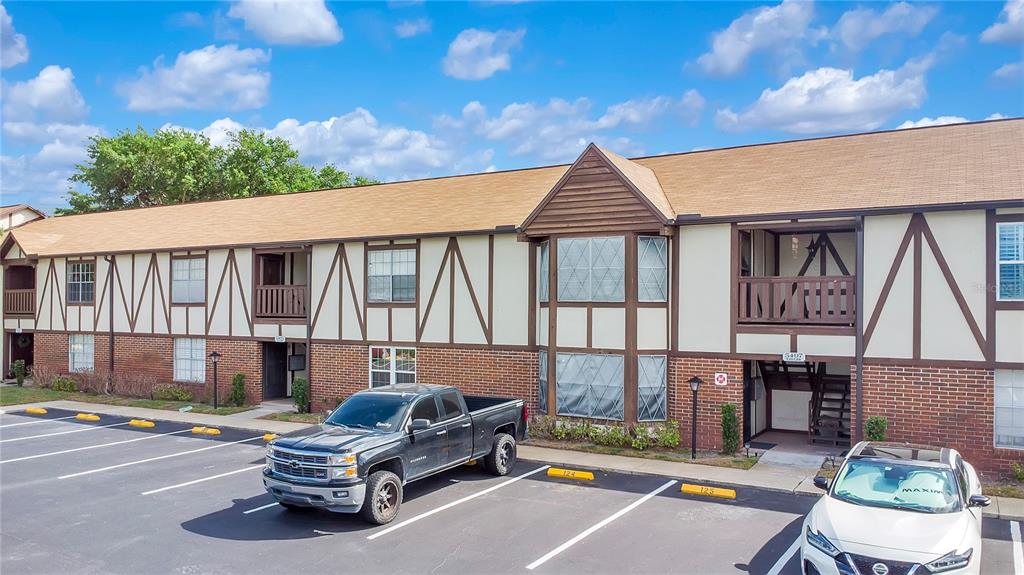 A two-story apartment building with Tudor-style exterior trim and a parking lot in front — 5407 HANSEL AVENUE UNIT G12, ORLANDO, FL