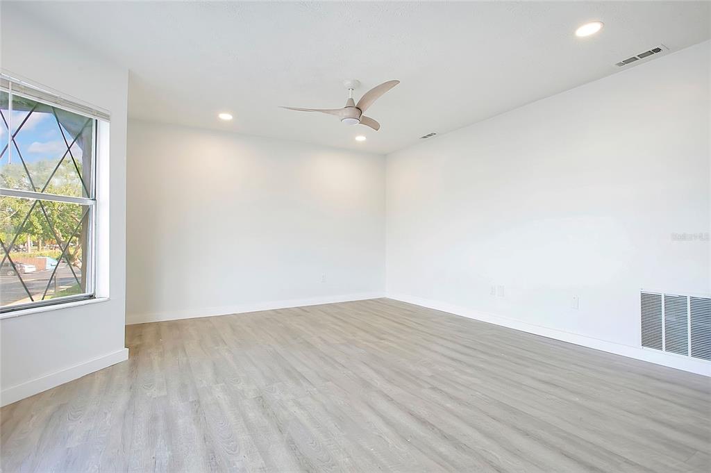 An empty room features light wood-look flooring, white walls, a ceiling fan, and a window — 5407 HANSEL AVENUE UNIT G12, ORLANDO, FL