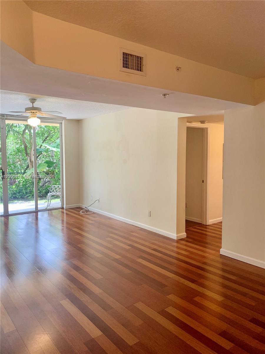 An empty living room features hardwood floors, a ceiling fan, and sliding glass patio doors — 529 E Sheridan St # 1021, Dania Beach FL 33004, DANIA BEACH, FL