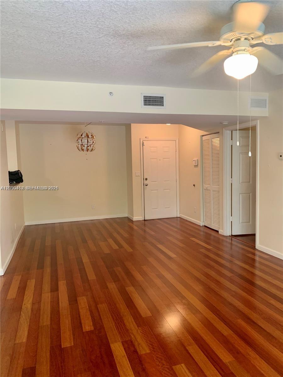 An empty room features hardwood flooring, a ceiling fan, and a white entry door — 529 E Sheridan St # 1021, Dania Beach FL 33004, DANIA BEACH, FL