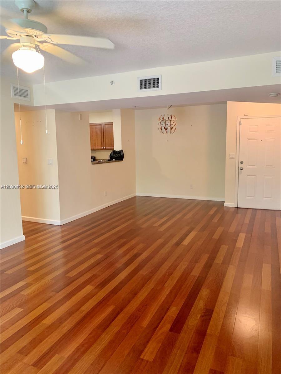 An empty living area features hardwood floors, a ceiling fan, and an open kitchen pass-through — 529 E Sheridan St # 1021, Dania Beach FL 33004, DANIA BEACH, FL