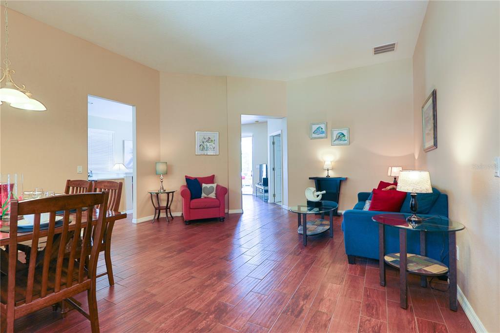 A living and dining area features wood-look tile flooring, beige walls, and blue and red furniture — 331 HENLEY CIRCLE, DAVENPORT, FL