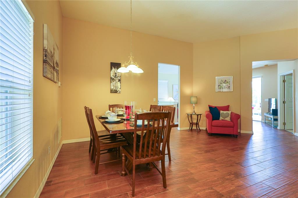 A dining room with a wooden table, chairs, and a red armchair on tile flooring — 331 HENLEY CIRCLE, DAVENPORT, FL