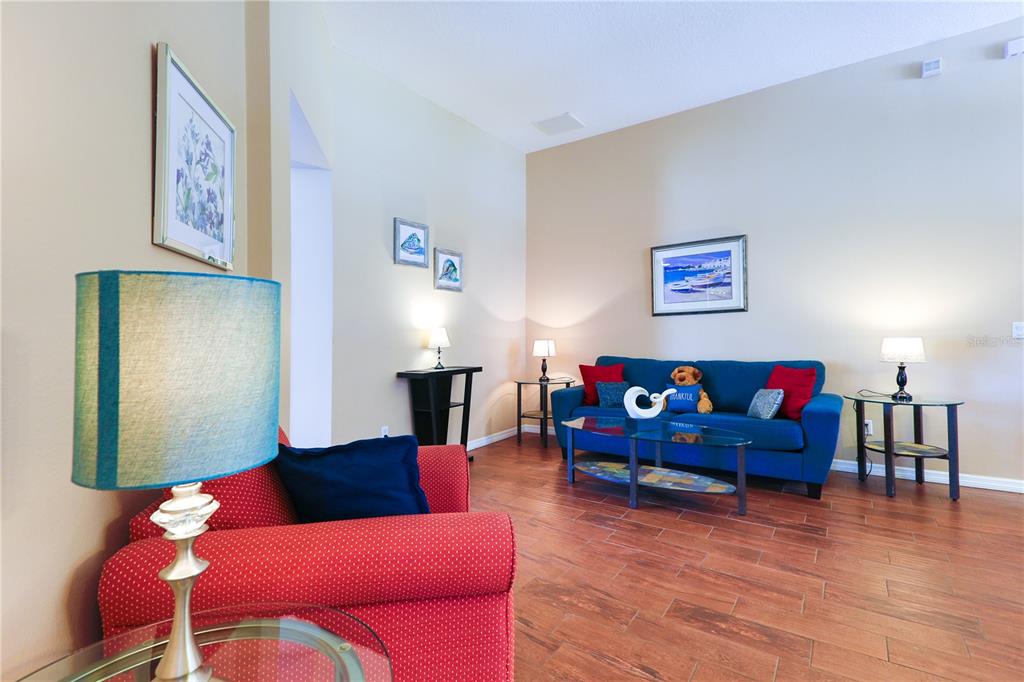 A living room features a blue sofa, a red armchair, and wood-look tile flooring — 331 HENLEY CIRCLE, DAVENPORT, FL
