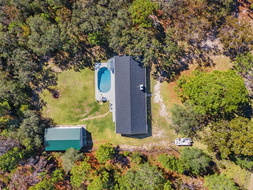 An aerial view shows a house with a pool, a detached garage, and surrounding trees — 17504 THOMAS BOULEVARD, HUDSON, FL