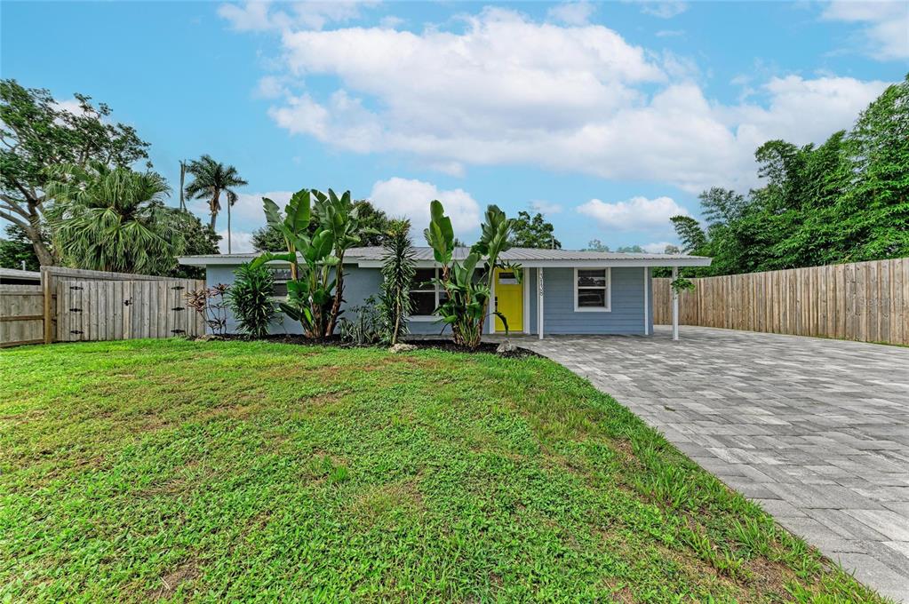 A single-story house with blue siding, a yellow front door, and a paved driveway — 3138 WILLIAMSBURG STREET, SARASOTA, FL