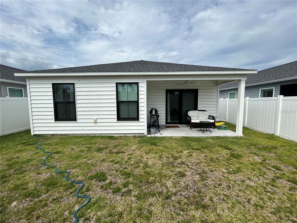 The exterior of a house features white horizontal siding, black-framed windows, and a covered patio — 7328 CATINAZZO COURT, MIDDLETON, FL