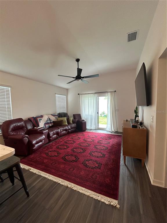 A living room features a large red area rug, a leather sectional, and a television — 7328 CATINAZZO COURT, MIDDLETON, FL