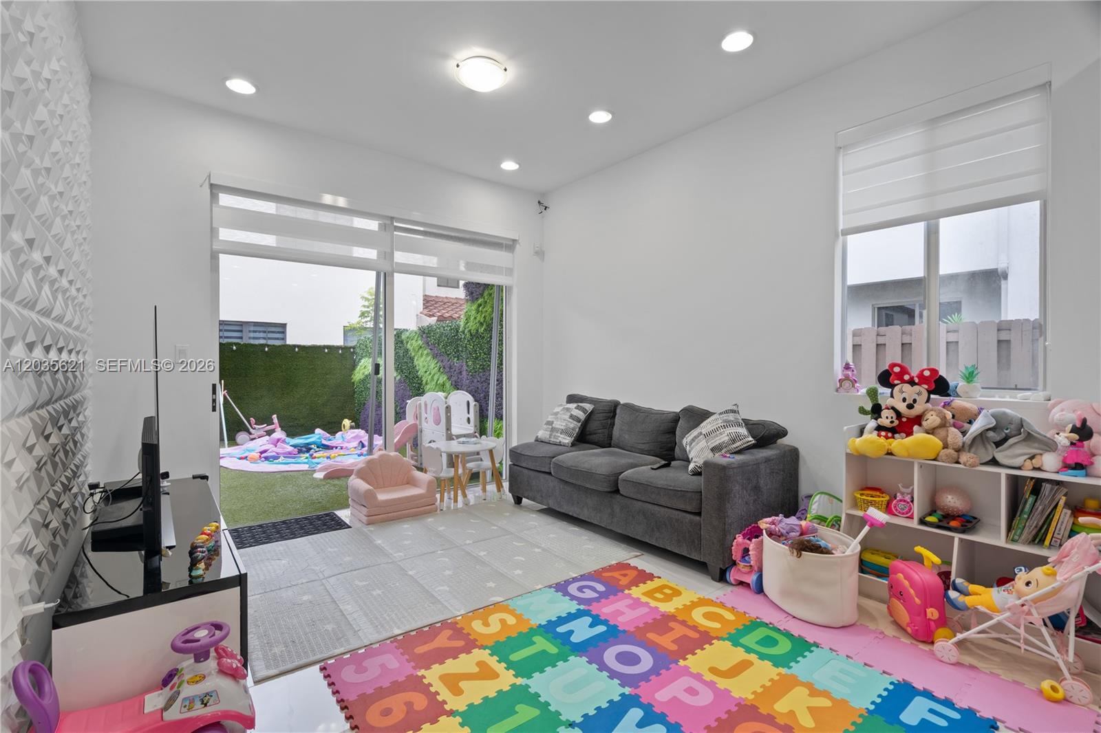 A playroom features a grey sofa, alphabet floor mats, a toy shelf, and a sliding door — 10294 NW 71st Ter, Doral FL 33178, DORAL, FL
