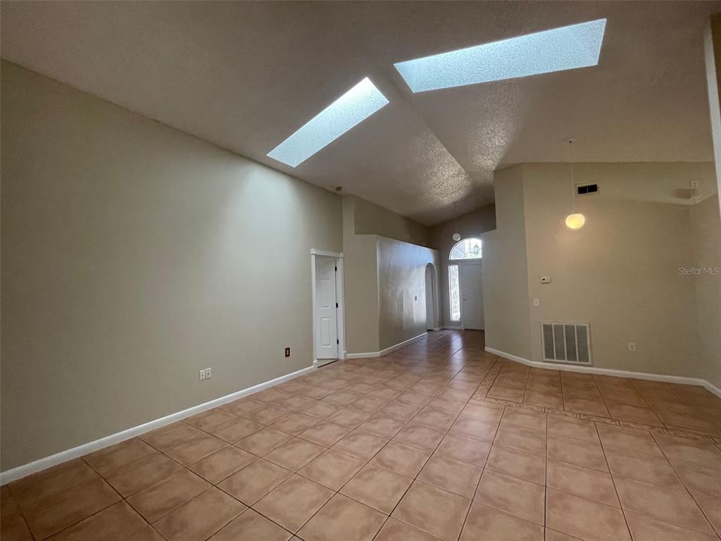 An interior view of a living area with vaulted ceilings, skylights, and tiled flooring — 4312 IVEYGLEN AVENUE, ORLANDO, FL