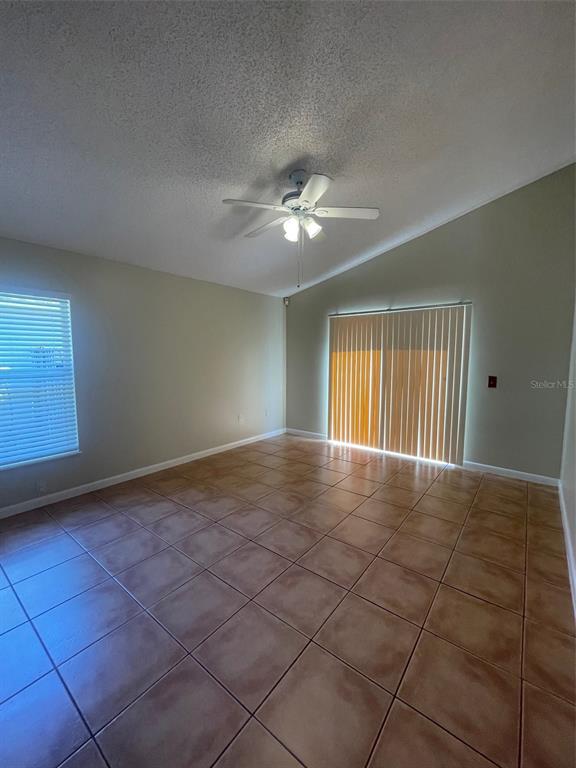A room with light-colored walls, a vaulted ceiling, a ceiling fan, and tiled flooring — 4312 IVEYGLEN AVENUE, ORLANDO, FL