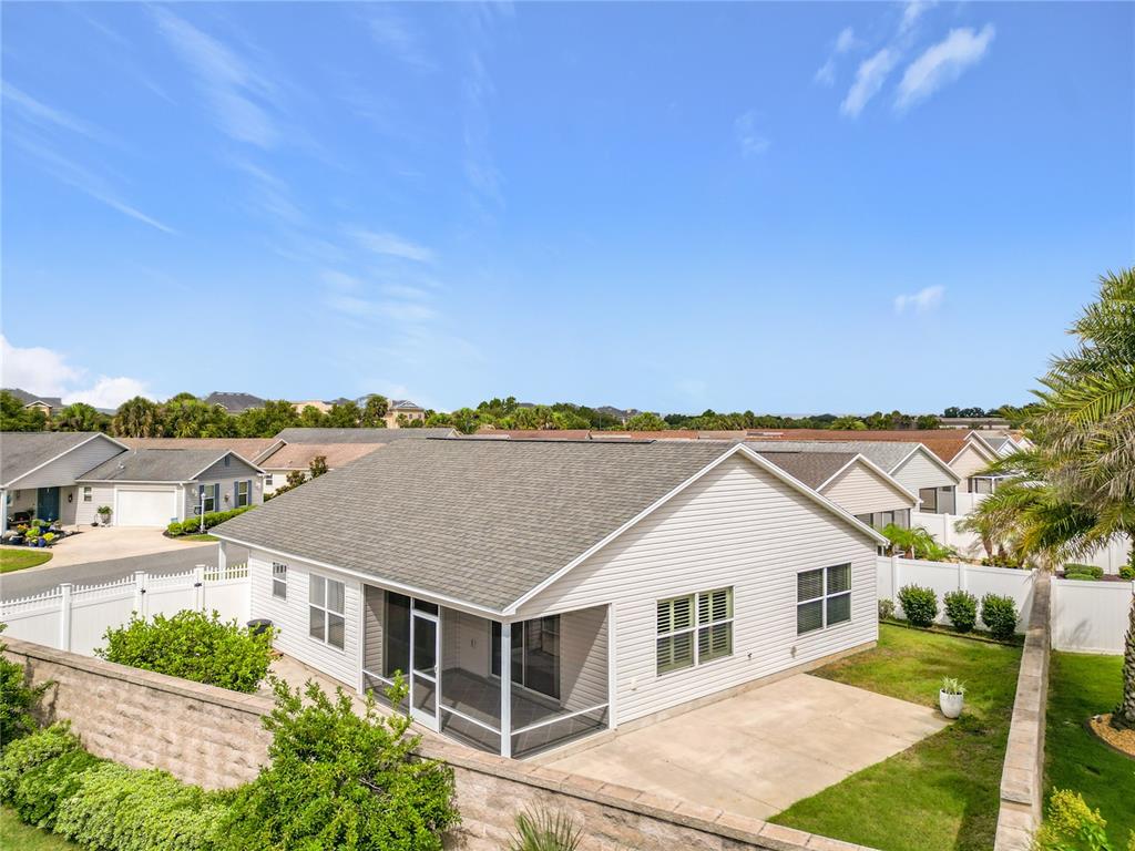 The exterior of a single-story house features light siding, a screened-in porch, and a concrete patio — 2565 LINDEWOOD STREET, THE VILLAGES, FL