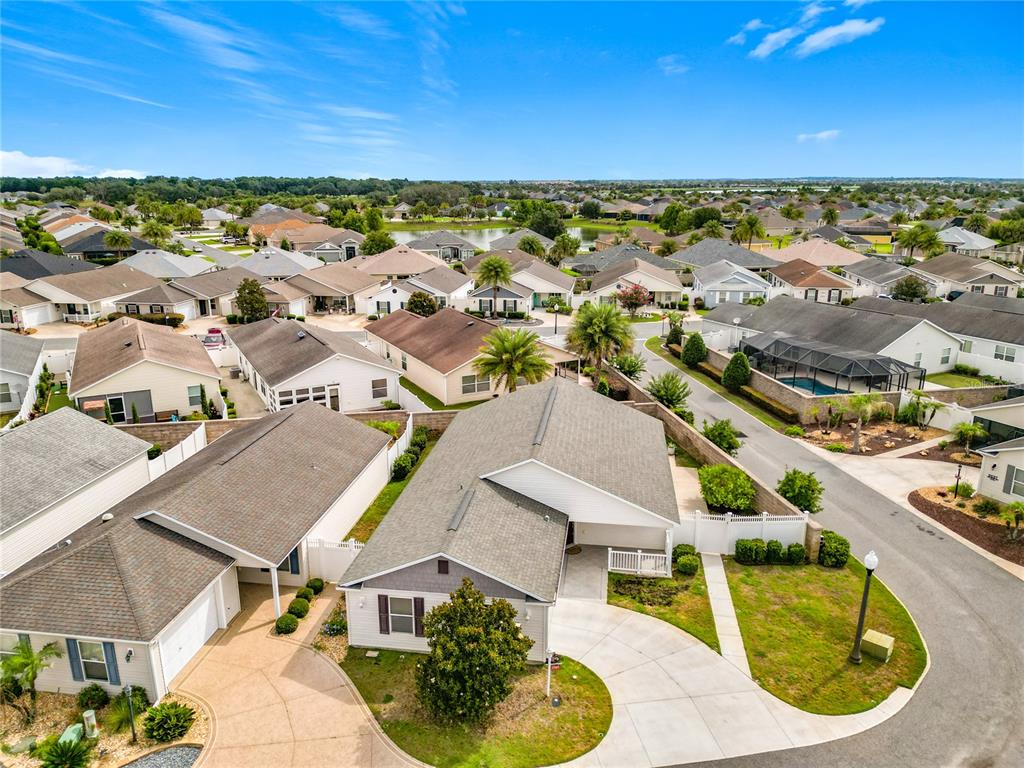 An aerial view shows a suburban neighborhood with single-family homes and a curved street — 2565 LINDEWOOD STREET, THE VILLAGES, FL